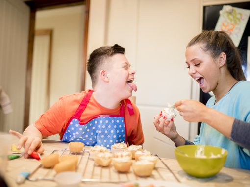 A boy with down syndrome bakes cakes with his sister in the kitchen.